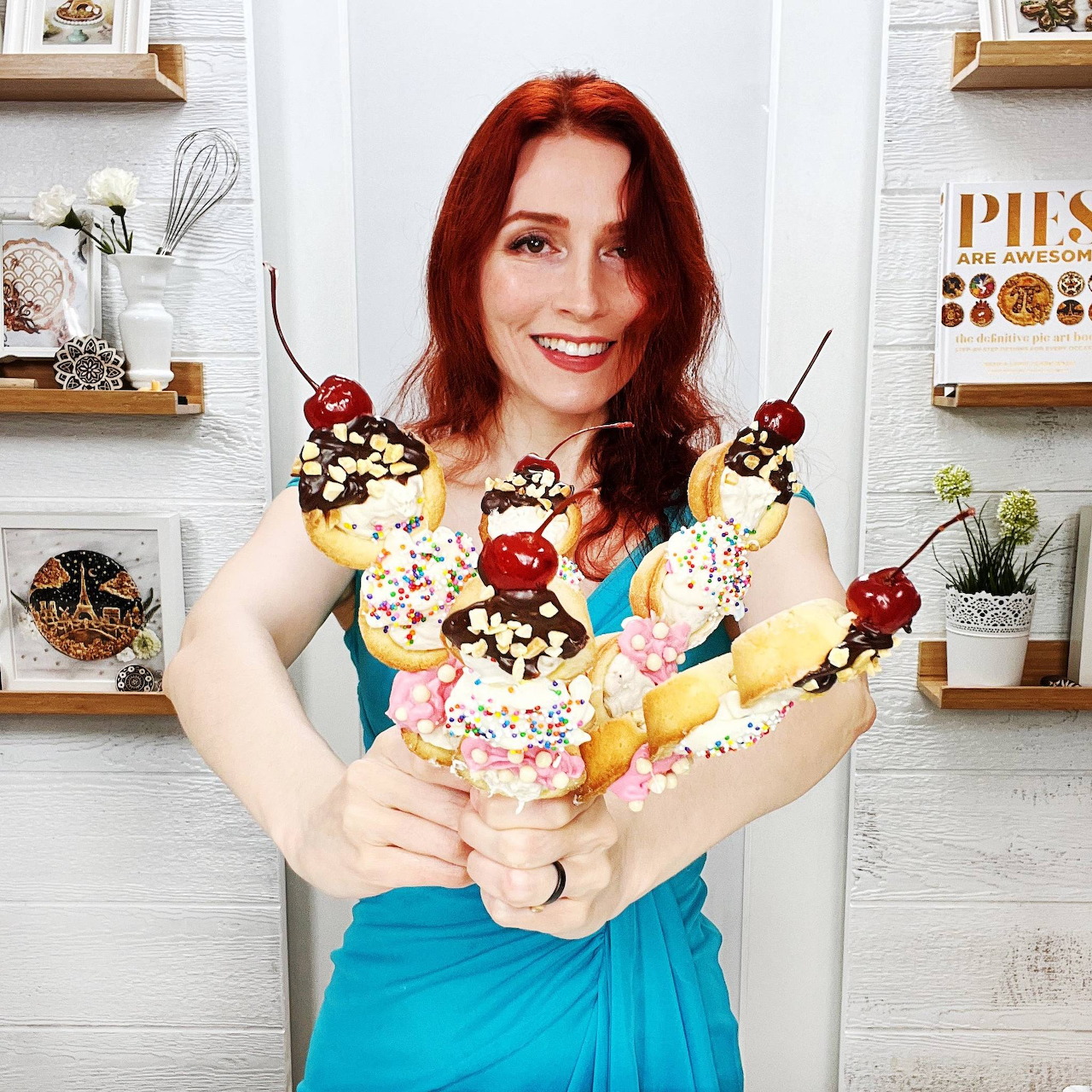 Woman with red hair holding several ice cream cones with whipped cream and cherries in a modern kitchen