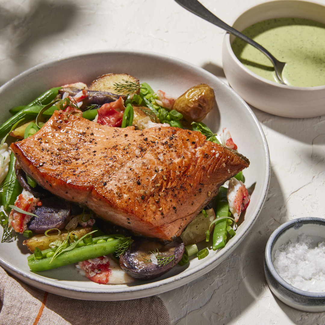 Grilled salmon fillet on salad with roasted vegetables, served with green soup and salt
