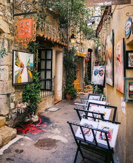 Narrow cobblestone alley in Mougins with stone buildings, ivy, art galleries and outdoor benches