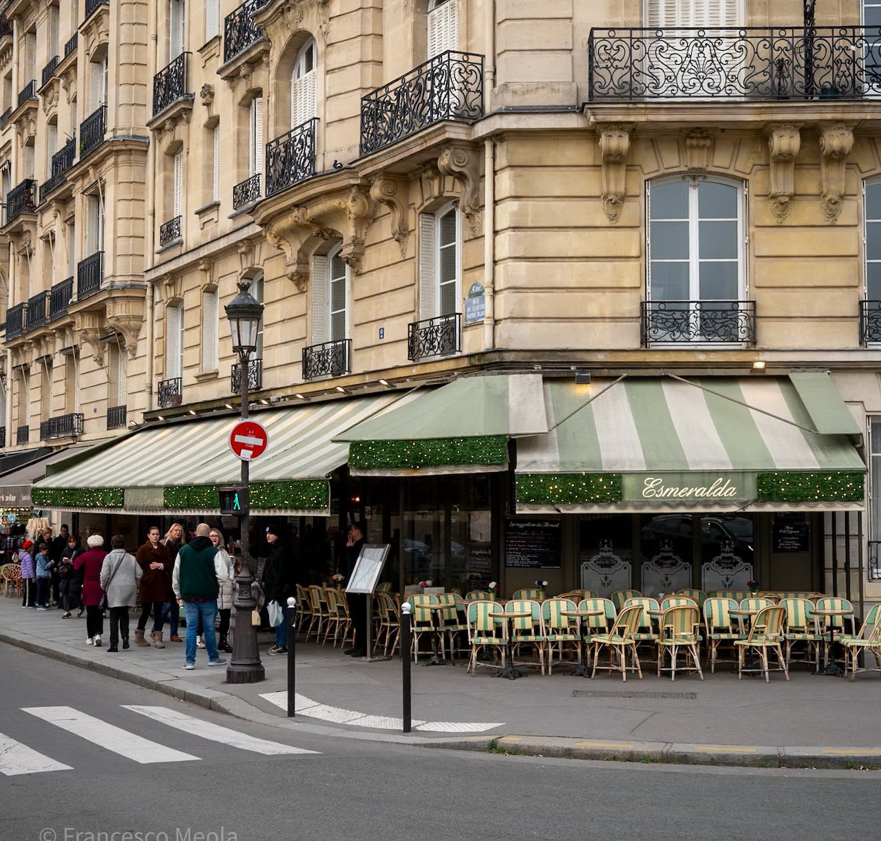 Paris street corner with Brasserie Esmeralda café, green awnings, and outdoor chairs