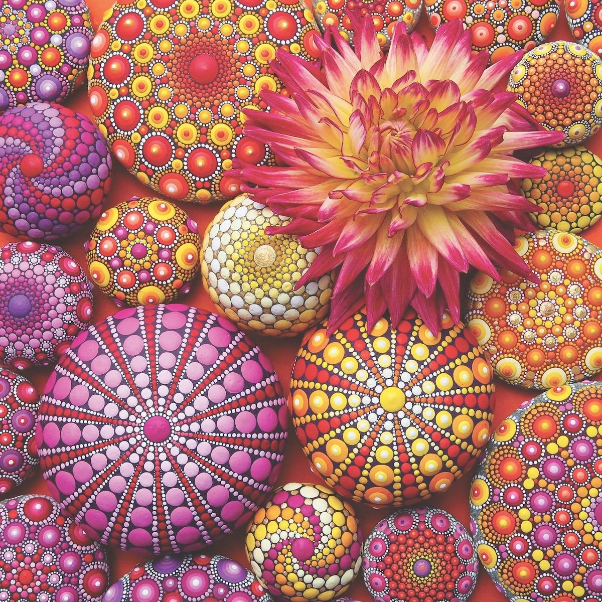 Colorful mandala dot painting with pink dahlia and geometric patterns in warm hues
