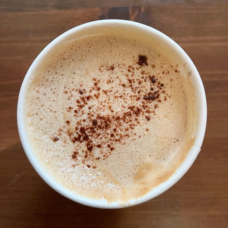 Overhead view of a chai latte with cinnamon spice dusting on milk foam in a white ceramic cup