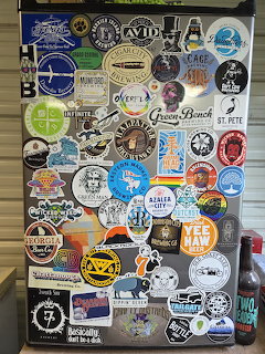 Refrigerator door covered with numerous colorful craft brewery and beer stickers