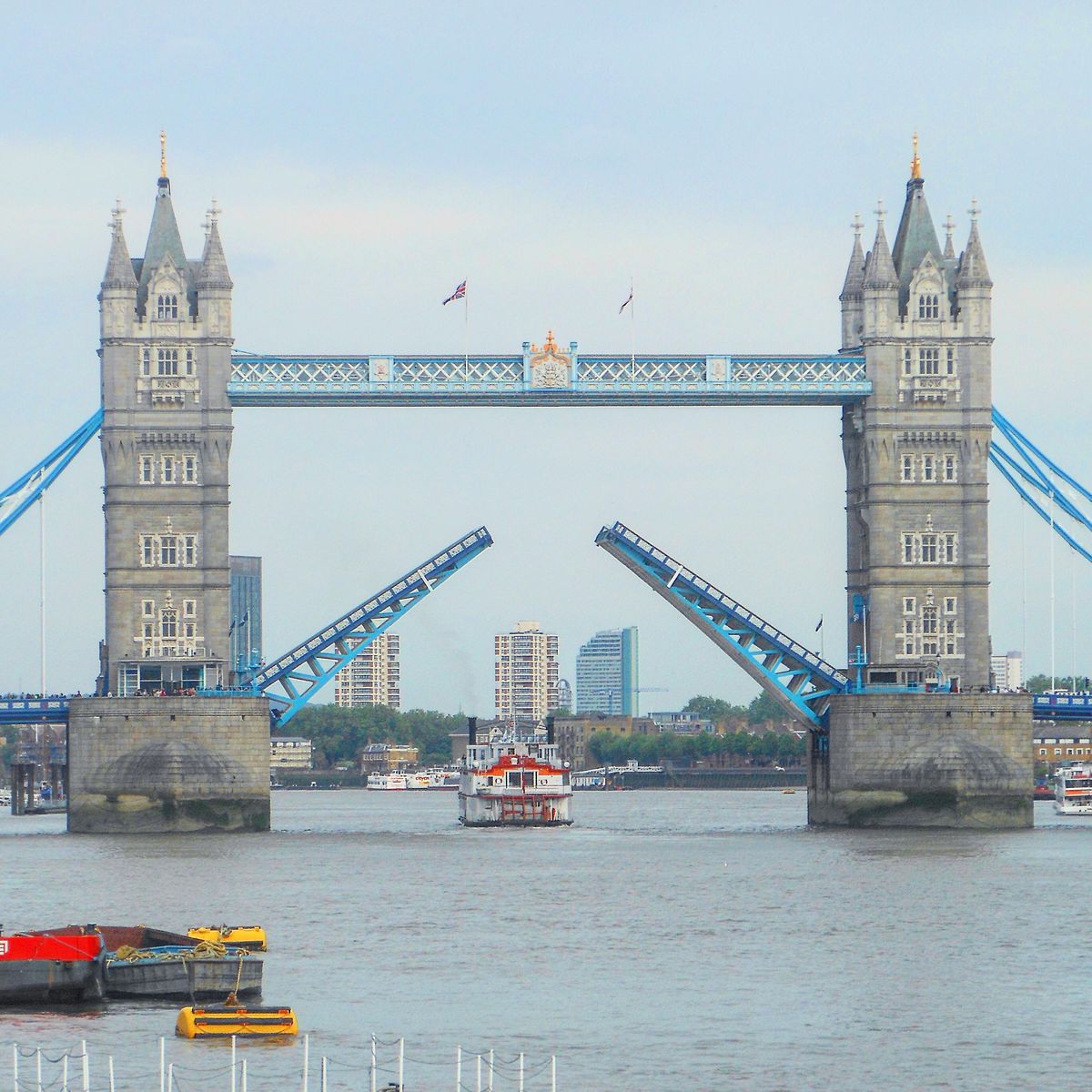 Tower Bridge in London raised over the River Thames with a small boat below