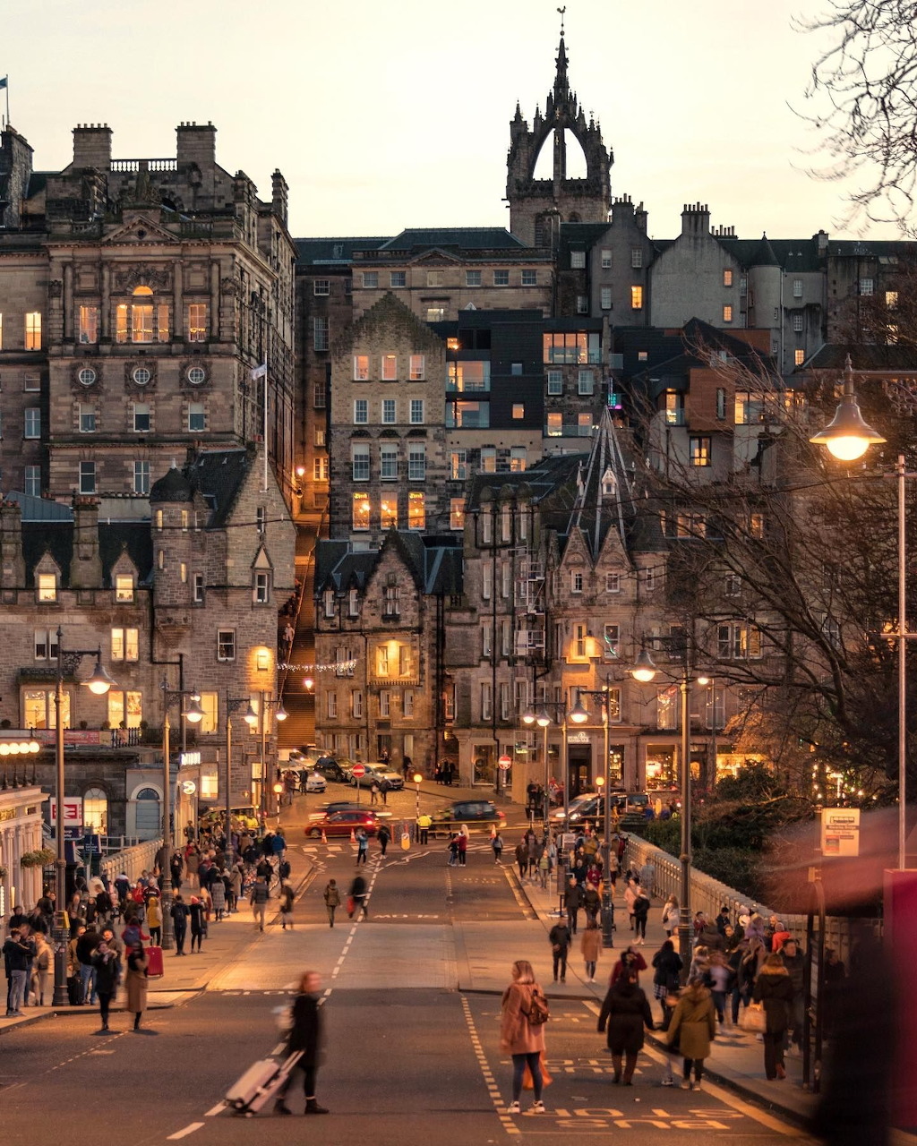 Edinburgh's historic Old Town at dusk with illuminated buildings and pedestrians walking cobbled streets