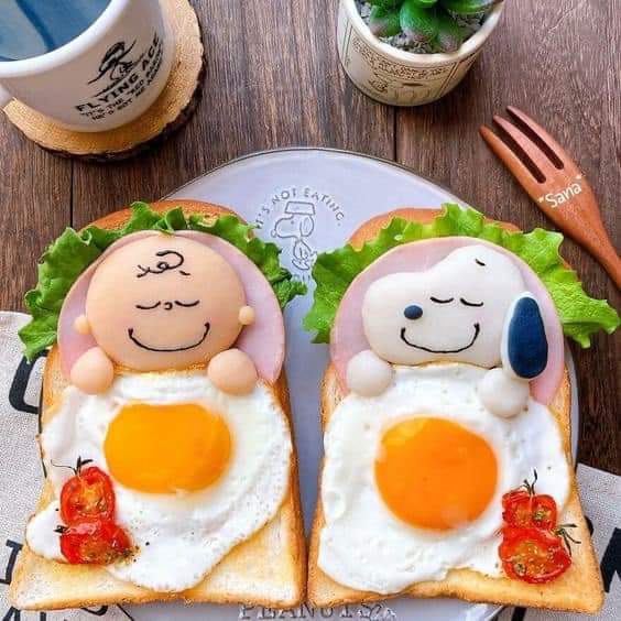 Two cute character toasts with fried eggs, lettuce, and tomatoes on a plate