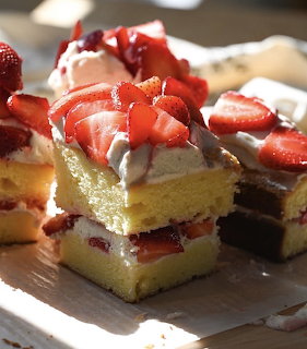 Stacked strawberry shortcake slices with whipped cream and fresh strawberries on a plate