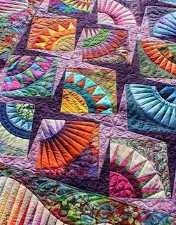 Colorful patchwork quilt with geometric fan and triangle patterns in rainbow hues