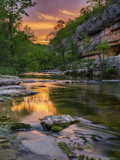 River flowing through canyon at sunset with golden sky reflection and limestone cliffs