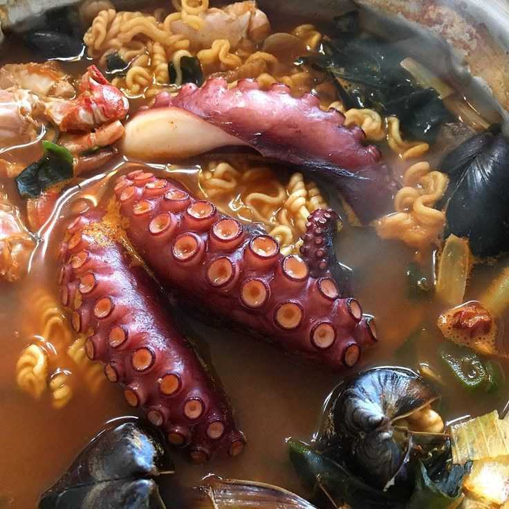 Ramen bowl with octopus tentacles, mussels, clams, and noodles in golden broth