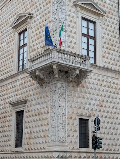 Corner of Palazzo dei Diamanti with diamond-point rustication, ornate pilaster, balcony and flags in Ferrara, Italy