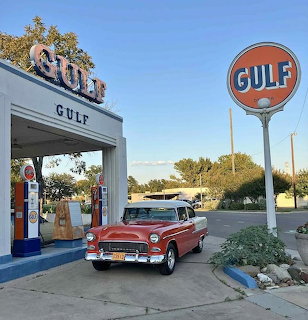 Red and white 1955 Chevrolet Bel Air at vintage Gulf gas station
