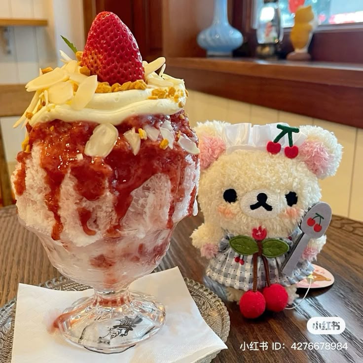 Strawberry parfait dessert with whipped cream and fresh strawberry next to cute plush bear on table