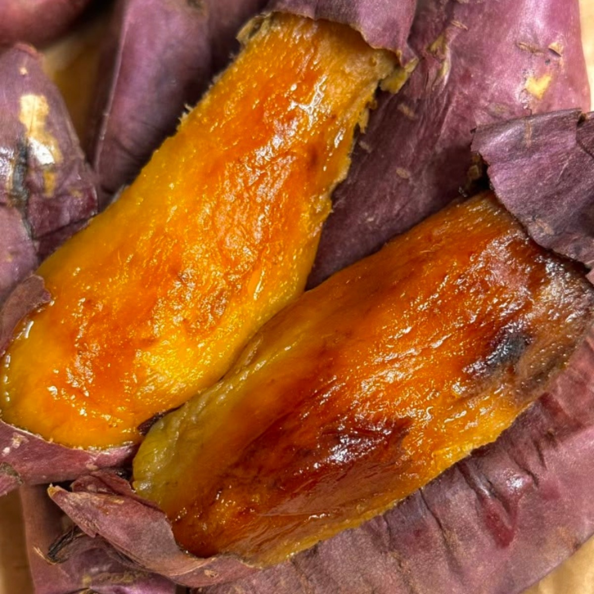Baked sweet potato split open showing caramelized orange flesh and purple skin