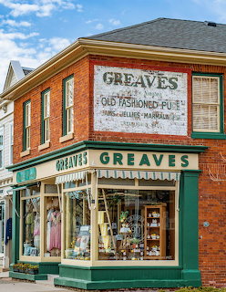 Red brick corner store with Greaves signage and green trim storefront