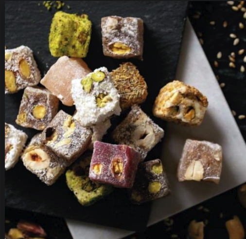 Assorted Turkish delight cubes with pistachios and nuts on a dark plate