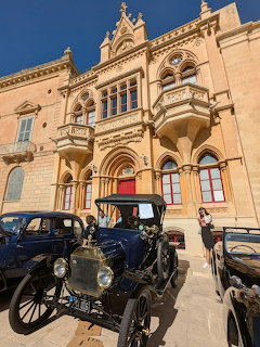 Vintage black classic cars parked in front of a historic limestone building in Mdina, Malta