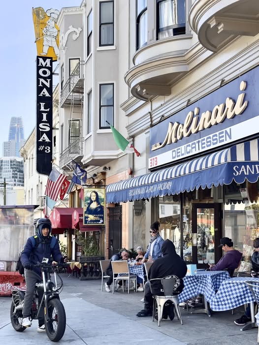 Mona Lisa Restaurant sign and Molinari Delicatessen storefront with outdoor diners on a North Beach SF sidewalk
