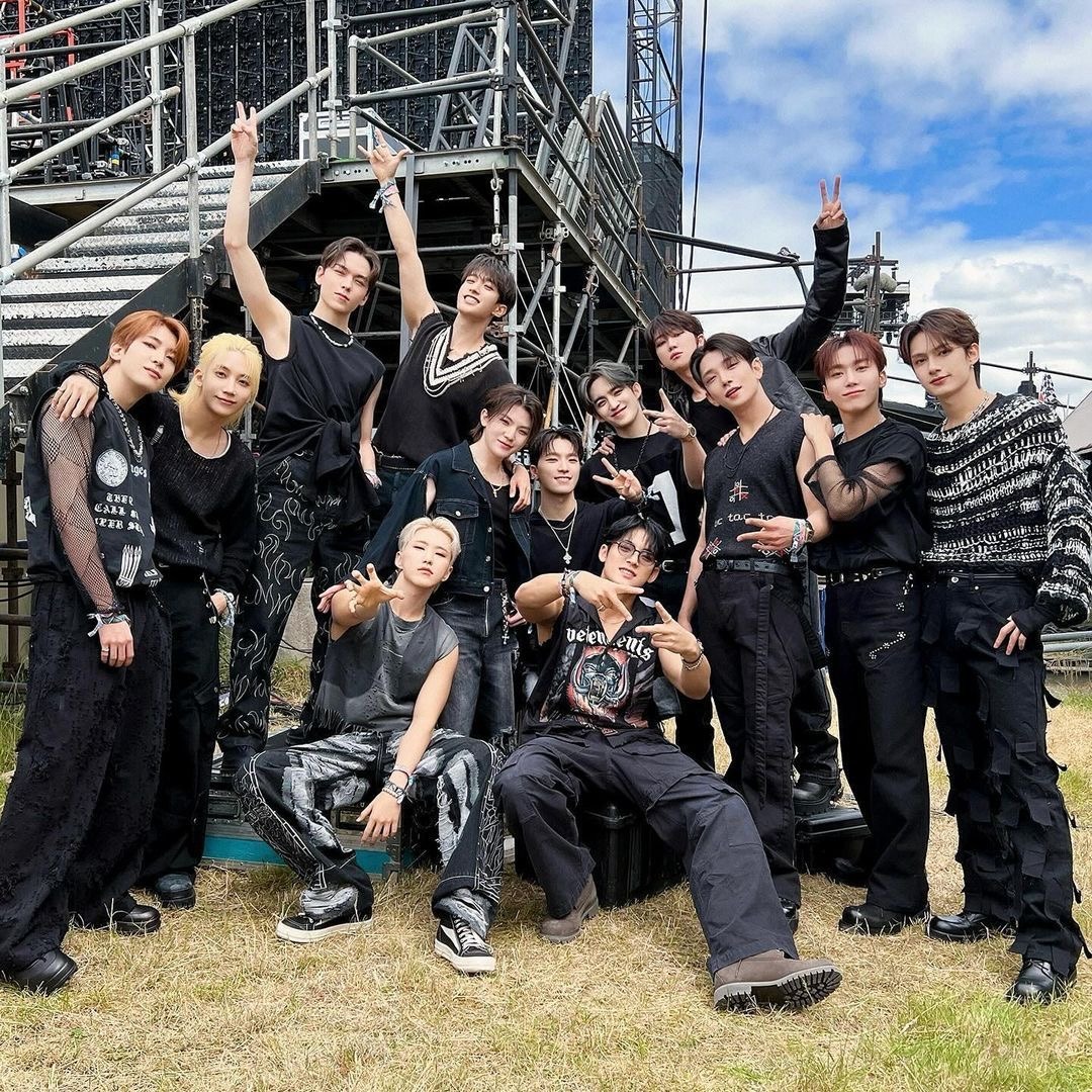 Group of young men in black outfits posing outdoors by metal scaffolding