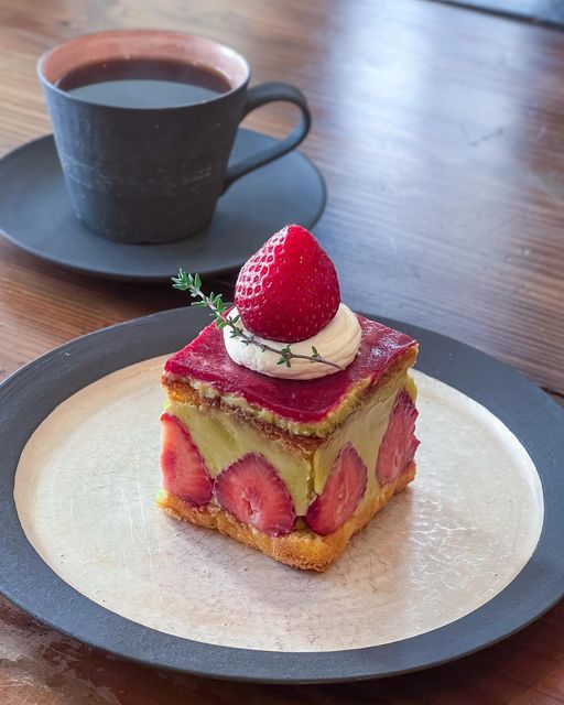 Layered strawberry cake with coffee on wooden table