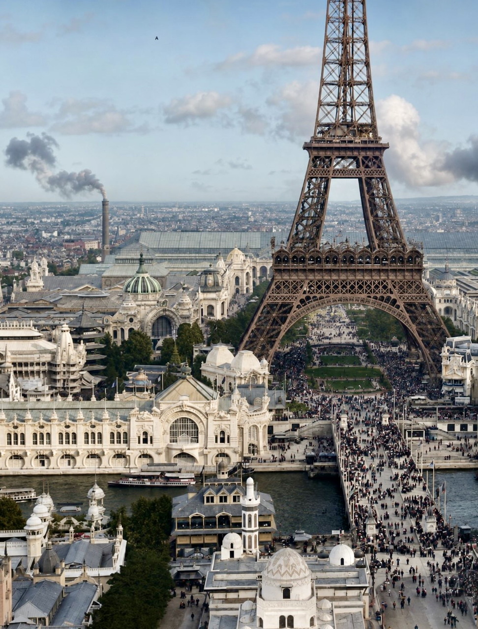 Eiffel Tower above Paris city buildings and a crowded bridge under a cloudy sky