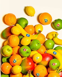 Assorted fruits including oranges, lemons, bananas, apples, and mangoes on a white background