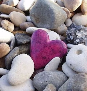 Pink heart-shaped stone among smooth gray and white pebbles