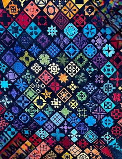 Colorful patchwork quilt with geometric patterns in blue, purple, red, and yellow tones