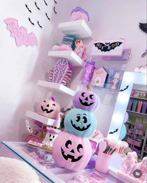 White shelf decorated with pastel pink and blue Halloween pumpkins, bats, and skeleton decorations