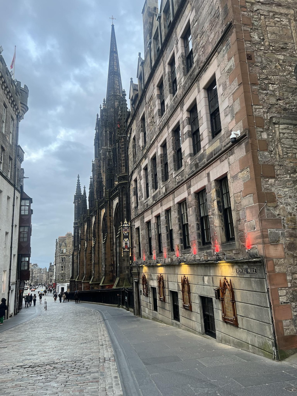 Cobbled Royal Mile street in Edinburgh with historic stone buildings and a tall spire