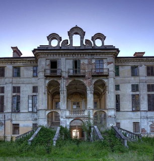 Abandoned baroque palace with deteriorating facade, ivy-covered stairs, and evening sky
