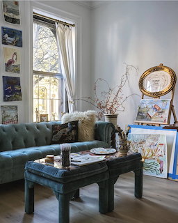 Cozy living room with teal sofa, black coffee table, window, and wall art