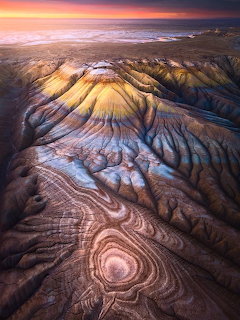 Aerial view of colorful striped mountain ridges with dramatic erosion patterns at sunset