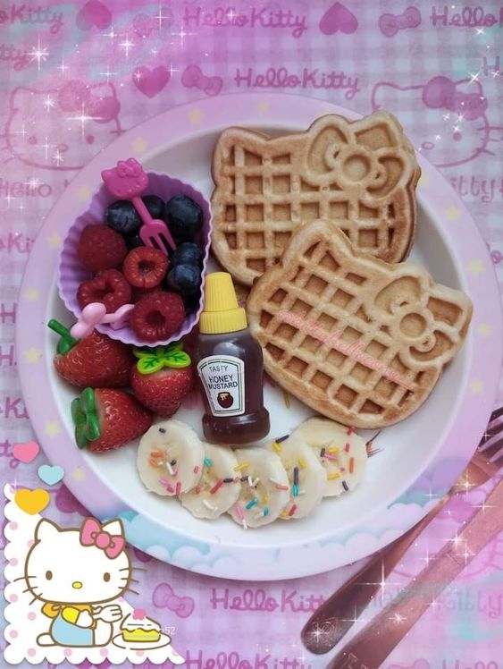 Hello Kitty shaped waffles served with strawberries, blueberries, and marshmallows on a white plate