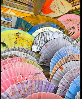 Overlapping decorative folding fans in multiple colors with painted floral and traditional patterns