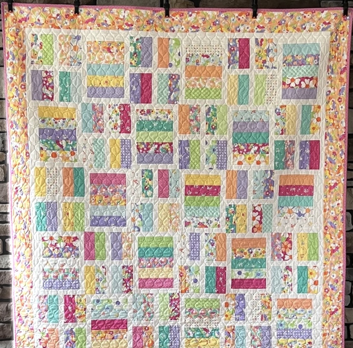 Colorful patchwork quilt with rectangular fabric blocks in pastel florals and patterns