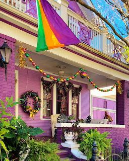Bright purple Victorian house with rainbow striped awning and festive decorations on porch