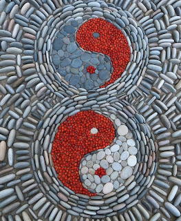 Two yin yang symbols created from red and blue-gray stones in circular mosaic pattern