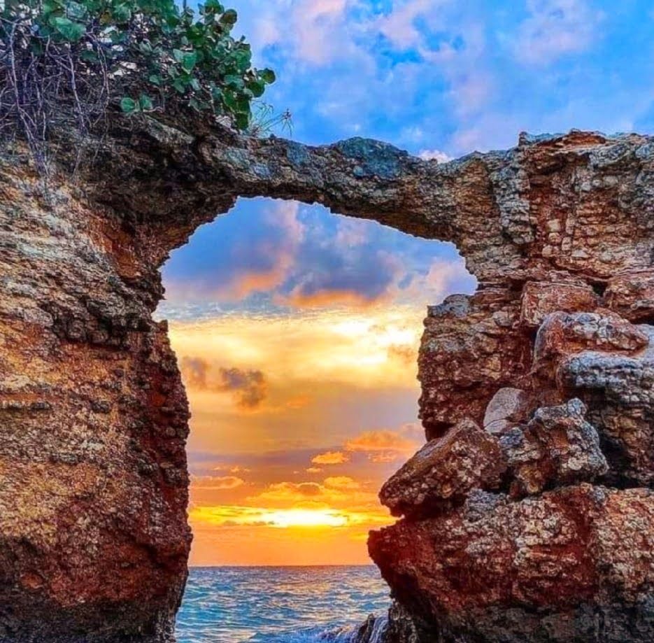 Rock arch on a seaside cliff framing a bright sunset over the ocean in Cabo Rojo, Puerto Rico