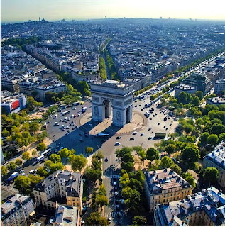 Aerial photograph of Arc de Triomphe in Paris with radiating streets and city skyline