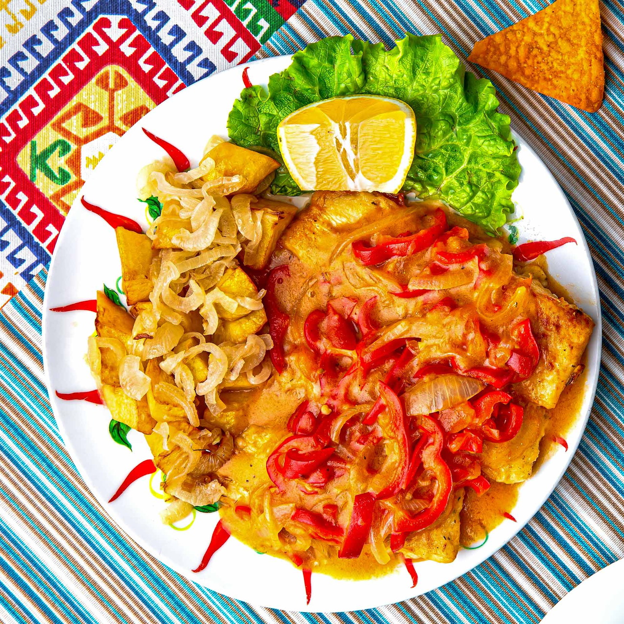 Overhead view of Korean kimchi varieties on white plate with lettuce and lemon garnish