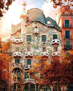Casa Batlló colorful mosaic facade with skull-like balconies framed by autumn trees in Barcelona