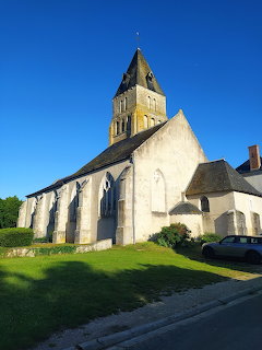 Old stone church with pointed bell tower against a clear blue sky on a sunny day