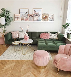 Modern living room with green velvet sofa, pink armchair and ottoman, gallery wall, and houseplants