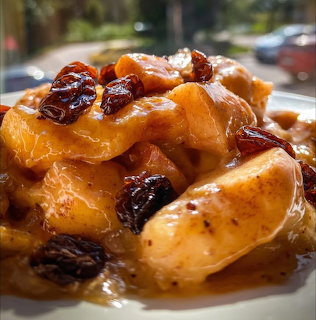 Close-up of caramelized apple slices and raisins in glossy sauce