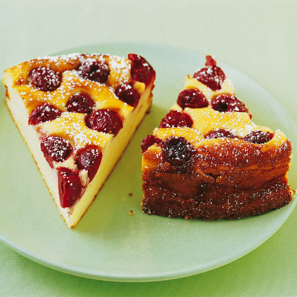 Two slices of yellow cake with raspberries and powdered sugar on a green plate