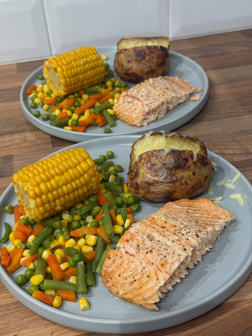 Salmon fillet with corn, potato, and vegetables on gray plate