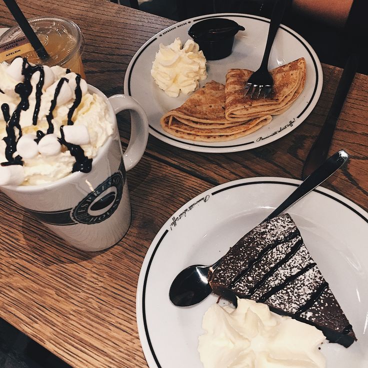 Coffee shop table with hot chocolate, crepes, and chocolate cake desserts on wooden surface