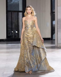 Fashion model in a shimmering gold strapless gown walking on an indoor runway