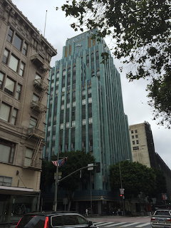 Turquoise Art Deco Eastern Columbia Building in downtown Los Angeles with trees and cars on the street